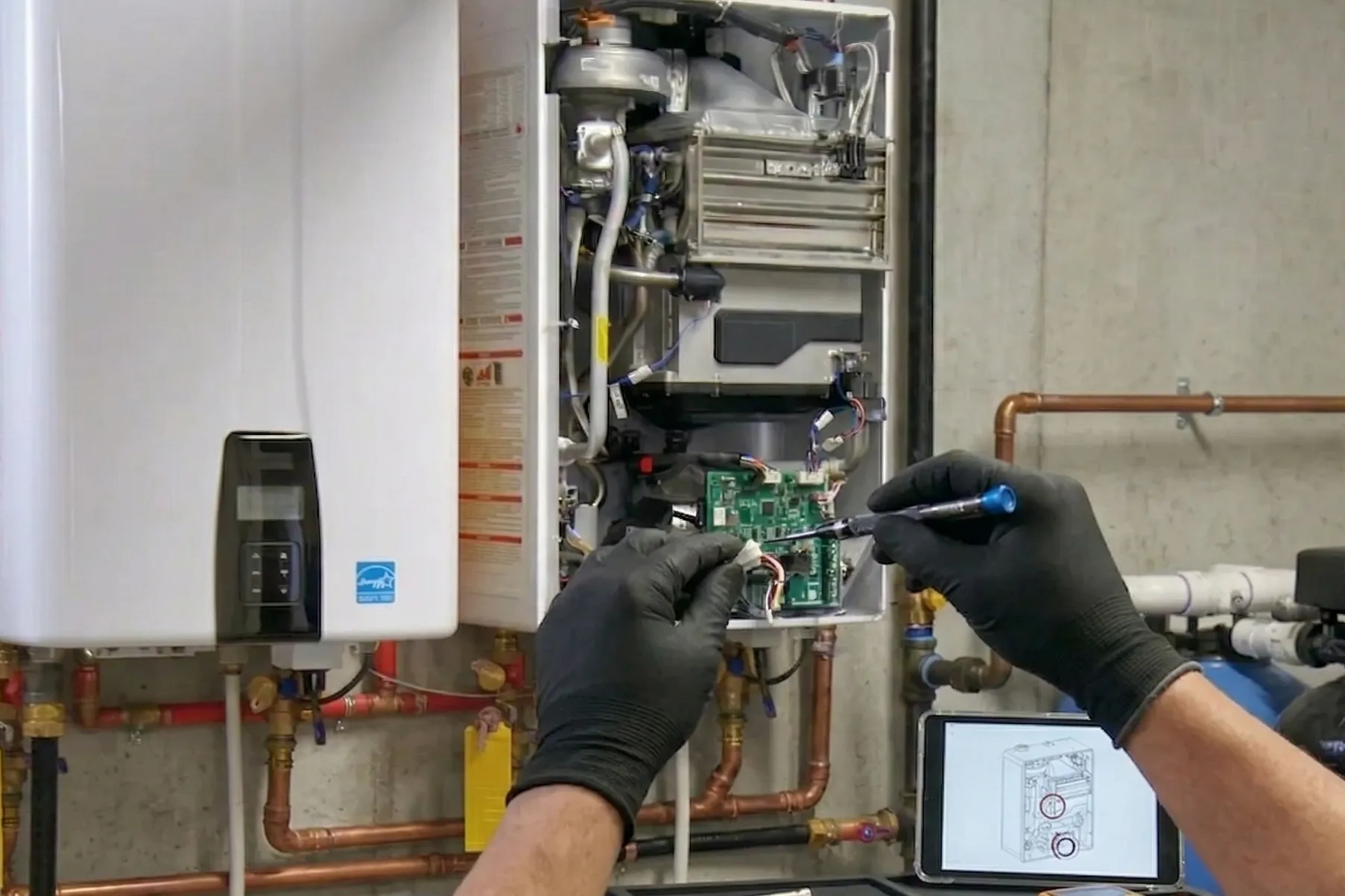 Plumber in black gloves servicing internal components of a tankless water heater during repair work